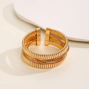 Detailed close-up of golden multi-layer spring-coil bracelet with industrial metal texture