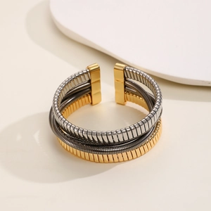 Detailed macro view of triple-tone gold silver and gunblack tubogas wrap bracelet