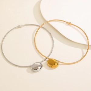 Detail of minimalist gold and silver chokers with pebble pendants and mirror finish