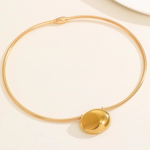 Close-up of golden collar necklace featuring a polished mirror-finish oval pendant