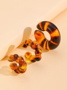 Close-up of three amber resin ear cuffs featuring smooth, beaded, and twisted textures