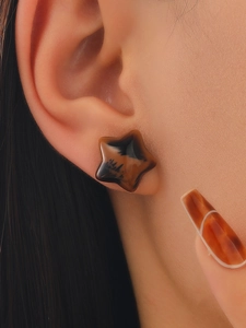 Macro view of leopard print star-shaped earrings with tortoise shell texture finish