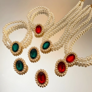 Detaillierte Nahaufnahme von Vintage-Perlenschmuck-Set mit roten und grünen Edelsteinen