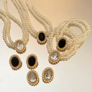 Detailansicht eines Vintage-Perlen-Schmucksets mit ovalen Kristallanhängern und Vergoldung