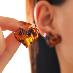 Detail of heart-shaped tortoiseshell earrings with a textured ribbed resin finish