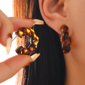 Macro shot of amber tortoiseshell twisted hoop earrings in semi-transparent resin