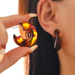 Macro detail of retro C-shaped tortoiseshell resin earrings with leopard print texture