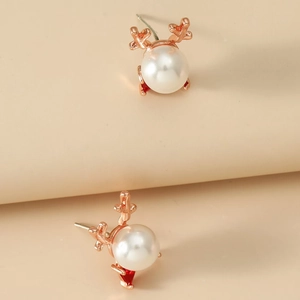 Macro shot of rose gold reindeer stud earrings with white pearl and red crystal accents