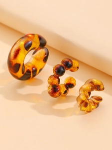 Macro detail of amber tortoiseshell resin C-shaped earrings with smooth and twisted textures