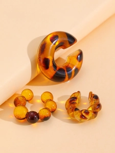 Detail view of 3-piece amber resin clip-on earrings with leopard and beaded textures