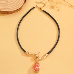 Detail van barokke parelketting met gouden takhanger aan een zwart lederen koord