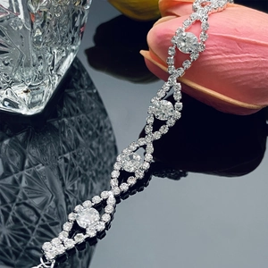Primer plano de pulsera de cadena plateada con pedrería brillante sobre fondo reflectante
