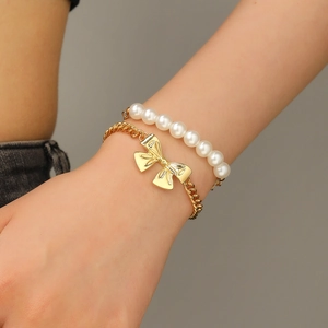 Nahaufnahme des Armband-Sets mit weißen Kunstperlen und goldenem Schleifenanhänger