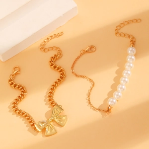 Details von Goldketten-Armbändern mit Schleifenanhänger und weißen Perlen im Set