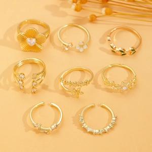 Detail van 8-delige set gouden open ringen met bloemmotieven en fonkelende strassteentjes