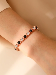 Detalle de una pulsera de oro rosa con cristales negros y blancos alternados en la muñeca