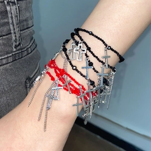 Detail eines mehrlagigen Perlenarmbands mit rotem Spinell und silbernen Kreuzen