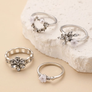 Detailopname van de 4-delige zilveren ringenset met witte parels en bloemige strass-accenten