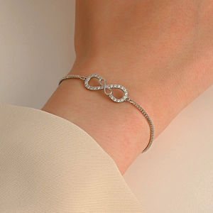 Detailed close-up of a silver infinity bracelet with pavé cubic zirconia on the wrist