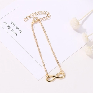 Detailed macro view of the gold infinity symbol charm on a minimalist chain bracelet