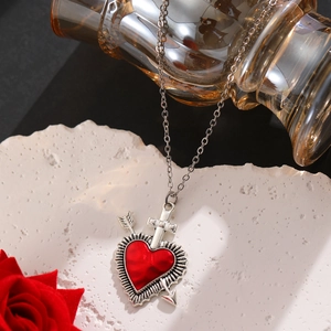Nahaufnahme der Gothic-Herz-Halskette auf weißem Stein mit roter Rose im Detail