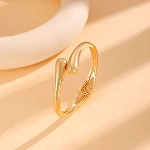Detailed view of golden spring cuff bracelet with polished teardrop design on display