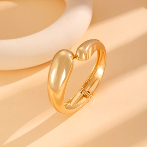 Detailed close-up of golden wide-surface spring bangle with smooth mirror finish