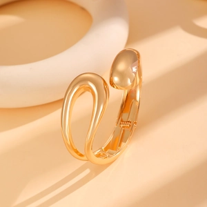 Detailed macro view of high-polish gold alloy cuff bracelet showing its smooth organic curves