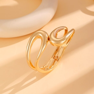 Detailed macro view of the golden geometric spring bangle with glossy asymmetric design
