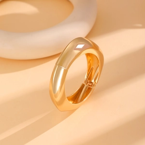 Close-up detail of polished gold wide cuff bracelet showing hinge and metallic gloss