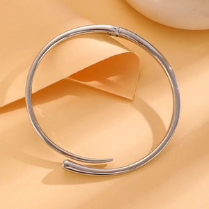 Detailed view of polished silver hinge bangle with minimalist overlapping design