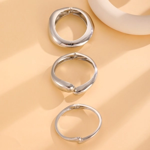 Detailed view of a three-piece minimalist silver metal ring set with polished geometric finish