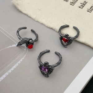 Detail of gothic punk crow claw ring with red gemstone and skull heart design