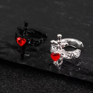 Macro shot of punk gothic heart ring with red zircon and silver sword engraving detail