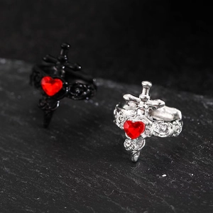 Detailed close-up of gothic silver and black rings with red heart stones and sword cross
