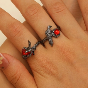 Gothic style rings featuring dark metal texture, bird motifs, and striking red gemstones