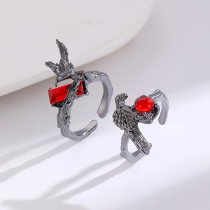 Detailed view of punk style dark metal rings with red gemstones and eagle claw designs