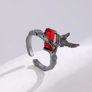 Macro shot of gothic style open ring with red gem and intricate metal wing texture
