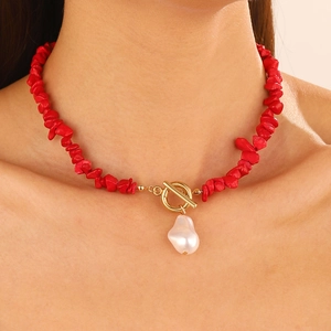 Close-up of red stone necklace featuring a Baroque pearl pendant and golden T-bar clasp