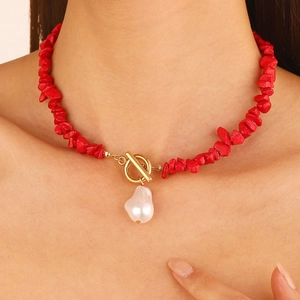 Detail of red stone choker with golden OT clasp and baroque pearl pendant on the collarbone