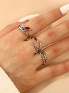 Macro detail of punk gothic silver rings featuring red drop stones on fabric background