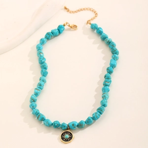 Detailed shot of turquoise beaded necklace with gold sun pendant and lobster clasp