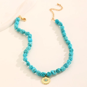 Close-up of bohemian turquoise beads and gold evil eye pendant on a delicate necklace