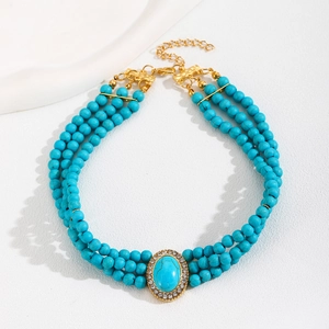 Detail of bohemian multilayer turquoise bead necklace with large oval pendant and gold accents