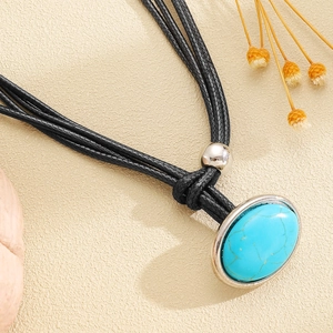 Macro detail of bohemian turquoise stone pendant with black braided cord and silver bead