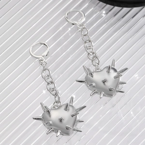 Détail de boucles d'oreilles punk argentées avec cœurs à pointes et chaînes épaisses
