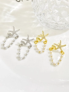 Dettaglio di orecchini a stella marina con perle e strass in oro e argento
