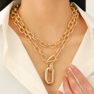 Detail of double-layer chunky gold chain necklace with decorative OT toggle clasp and pendant