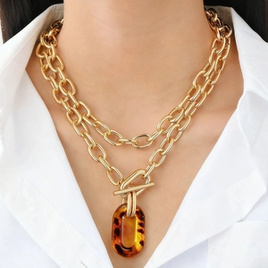 Detail of double-layer gold chain necklace with OT toggle and amber leopard resin ring