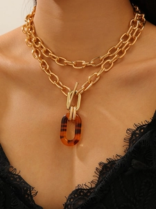 Detail of layered gold chain necklace featuring a vintage amber resin pendant and OT buckle